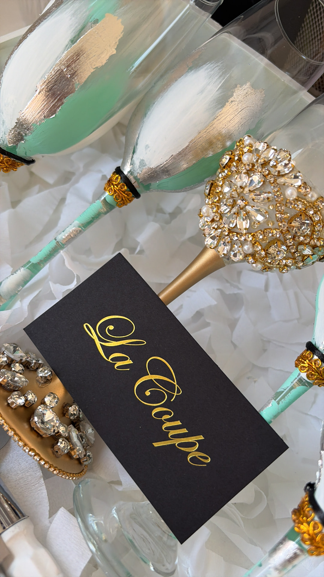 Detalle artesanal de copas pintadas en aqua, blanco y dorado con cristales