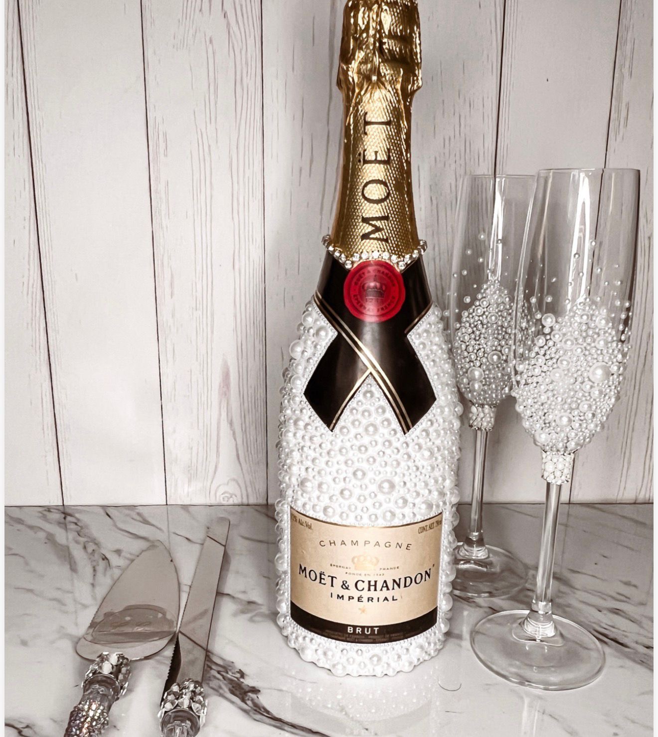 Botella de champagne y copas decoradas completamente con perlas blancas